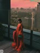 A woman in a red dress standing on a balcony.