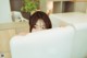 A woman peeking over the edge of a white refrigerator.