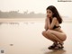 A woman in a black bikini sitting on a beach.