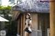 A woman in a black bathing suit standing in front of a hut.