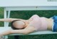 A woman laying on a white bench with her eyes closed.