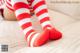 A woman wearing red and white striped stockings laying on a bed.