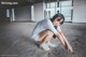 A woman crouching down on the ground in an empty room.