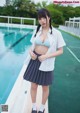 A woman in a school uniform standing next to a swimming pool.