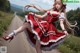 A woman in a red and white dress is dancing on a dirt road.