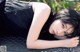 A woman laying on the ground with her head resting on a manhole cover.