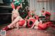 A woman in a red outfit laying on a rug next to a Christmas tree.